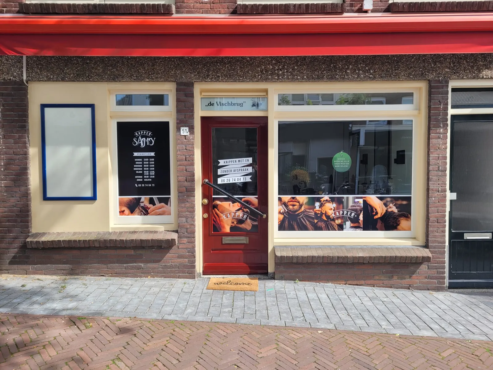 De gevel van Rijnstraat 51 met de rode luifel en de ossenbloedrode deur