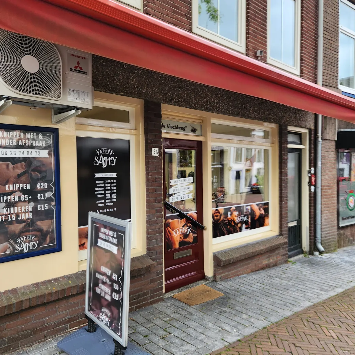 De gevel schuin van opzij, met het prijsbord en het stoepbord