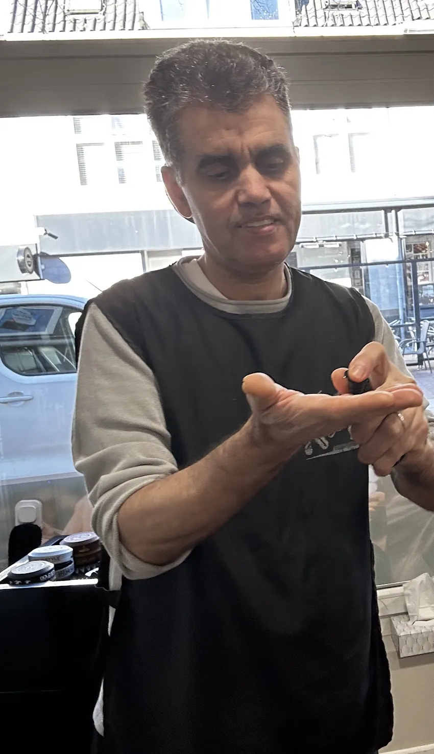 Samy legt aan een klant uit hoe hij het gaat knippen
